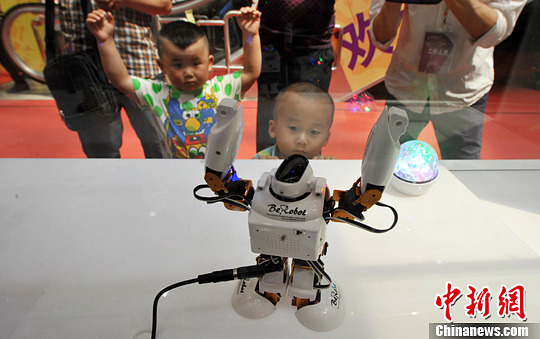 在智慧生活体验馆内，台湾机器人的热舞深深吸引了孩童的眼球，有个男童还手舞足蹈地和机器人一起跳了起来。中新社发 翟羽佳 摄
