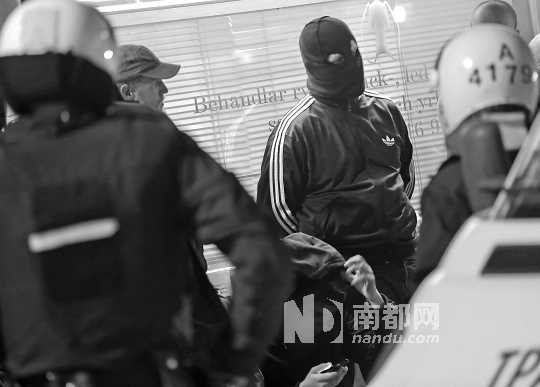 25日,在瑞典斯德哥尔摩市郊,防暴警察对一名蒙面人进行搜身.