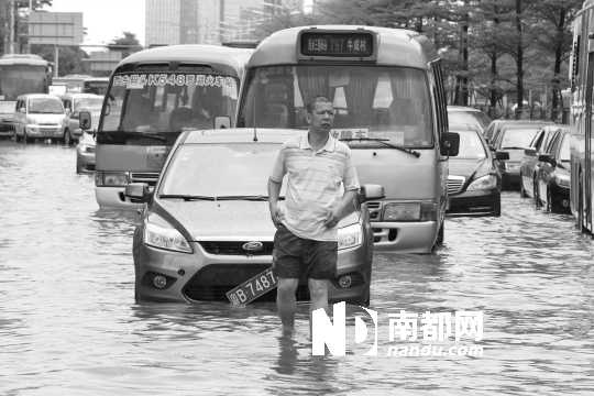 宝安西乡创业路积水严重，多辆轿车和中巴车熄火，有车主站在水中等待救援。南都记者 徐文阁 摄
