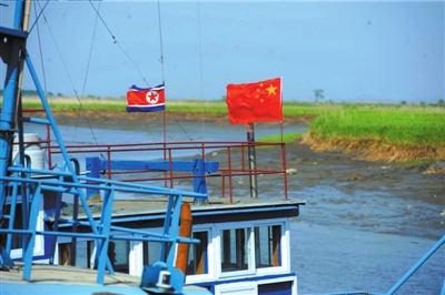 5月23日，在丹东东港附近的鸭绿江支流处，不少渔船都悬挂了中国与朝鲜的两国国旗。京华时报记者王苡萱摄