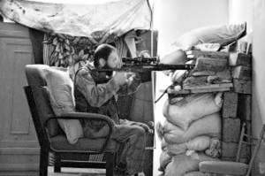 6月12日，在叙利亚的代尔藻尔，一名武装人员通过墙上的洞进行瞄准