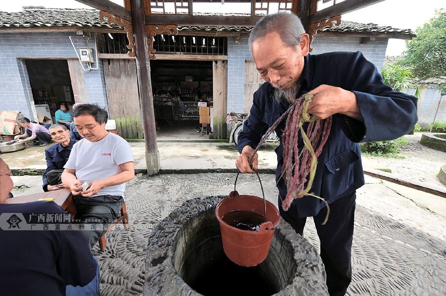 79岁的卢新连在井边打水.