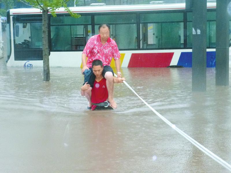 暴雨被困司机骑在消防员脖子上蹚水(高清图)