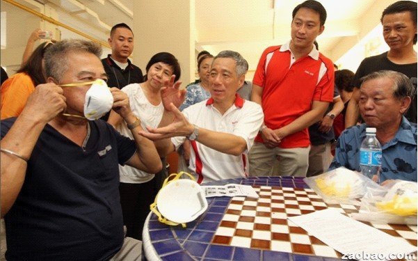 新加坡总理李显龙给民众示范如何戴上N95口罩。