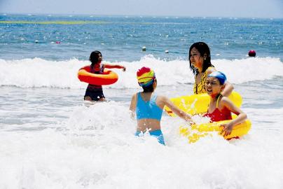 游客在山东青岛金沙滩海水浴场嬉戏(图)