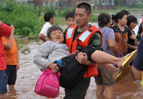 7月1日，在潼南县柏梓镇，消防战士抱着被救出的受灾群众走向安全区域。新华社记者 刘潺 摄
