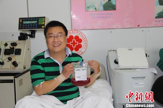 孟光军手持其捐献的203毫升造血干细胞悬液 申玲敏 摄