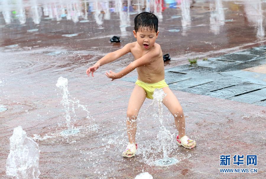 7月3日,在济南市泉城广场,一名小朋友在音乐喷泉旁戏水纳凉.