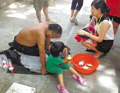 3日,南京,小女孩正坐在路边乞讨,身旁跪着她的父亲.