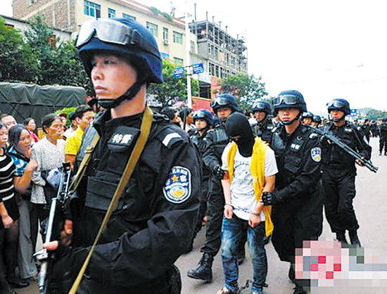 去年9月,警察押解两人在云南富源县犯罪现场进行指认,图中戴头套者为