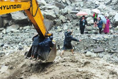 7月10日，汶川县映秀镇张家坪村，山洪阻断道路，挖掘机将被困的受灾群众转移到安全地带。