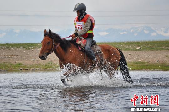 比赛中，选手们骑马涉水经过湖泊。　杨晓东　摄