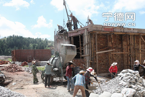 7月18日,工人们在周宁县礼门乡造福工程工地灌水泥.