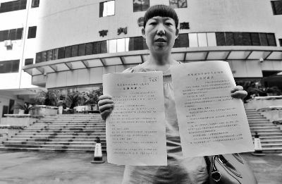 走出法庭后，李君给记者展示她此前告赢沃尔玛的判决书。摄/记者 刘畅
