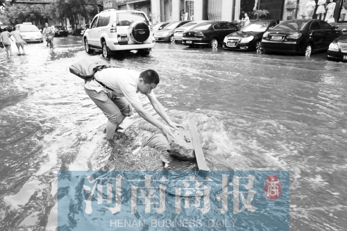 市民搬来石块放在被大水掀起的窨井盖上，警示路人