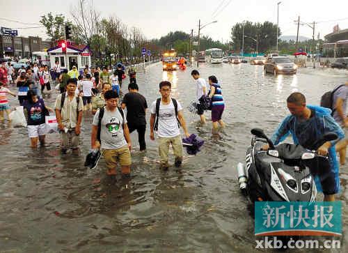 昨日,暴雨造成北京西苑地铁站门口积水,市民蹚水前行。新华社发