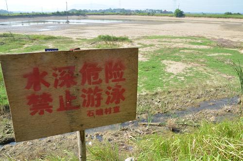 8月11日,在安徽省巢湖市槐林镇,一口干涸的水塘边竖立着丰水时的警示