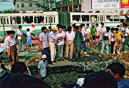 1988年6月8日，朱�F基在西藏中路和北京路十字路口察看自来水管爆裂情况。