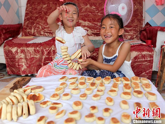 山东省文登市泽库镇姚家村的留守儿童11日在村里老人的指导下制作“巧果”，迎接中国传统七夕节。王娇妮 摄