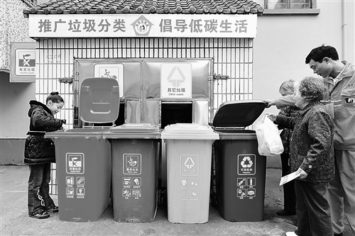 杭州开始试行生活垃圾分类处理,一位居民将已分类的垃圾投入到对应的垃圾桶内。