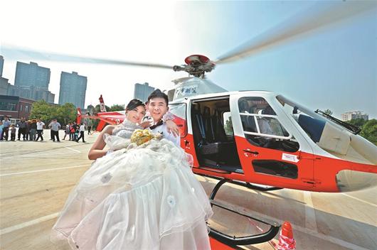 楚天都市报讯 图为：新郎抱着新娘走下直升飞机