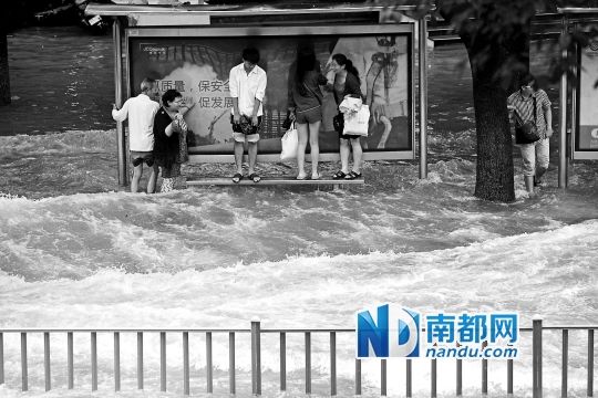 宁波市兴宁路积水严重,等公交的市民站到高处。新华社发