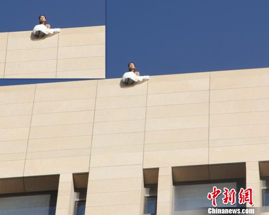 图为身着婚纱的女子坐在15楼楼顶。 王有德 摄