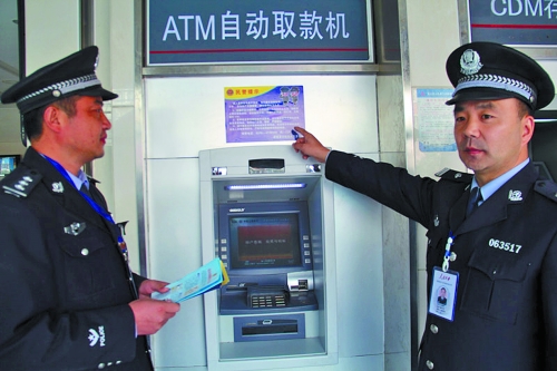 民警在ATM机上粘贴防诈骗提示，但效果不佳。