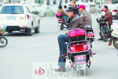 郑州街头,多辆“摩的”在路口等客。