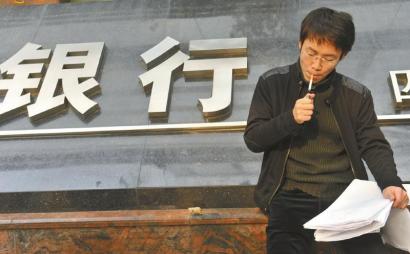11月18日，在银行门口的陈先生无助地抽着烟。