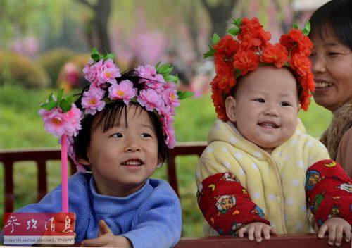 两名头戴牡丹花帽的幼童,在洛阳市的一个公园玩耍(2013年4月3日摄)。新华社记者王颂摄