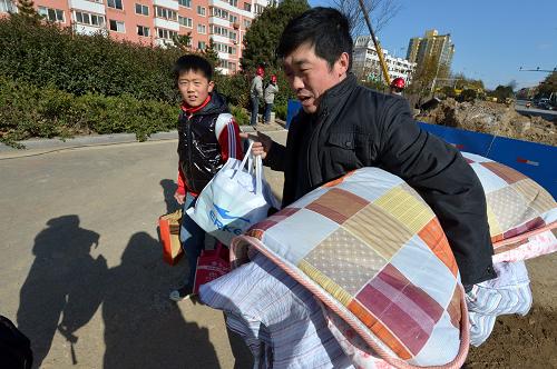 11月27日,一名学生家长拿着孩子的被褥衣物,陪着孩子从青岛开发区第二