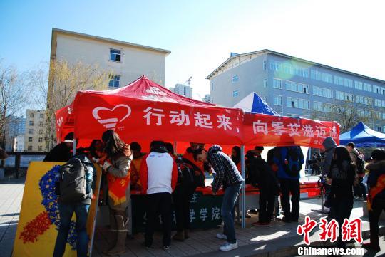 “防艾”志愿者邀请大学生签名抗击“艾滋病”。大学生大方接受安全套。 金涛 摄