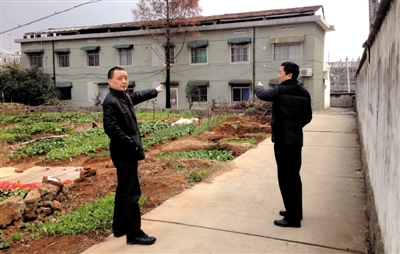 12月18日,被停职半月的陈龙(左)指着自己家所在的两层建筑。新京报记者 刘刚 摄
