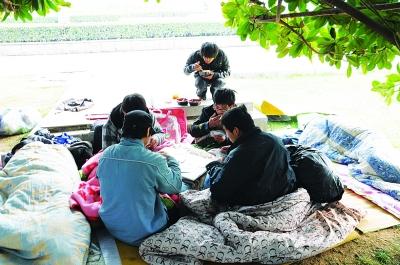 4名流浪汉在玩扑克,另一名流浪汉在一旁吃捡来的剩饭剩菜。见习记者杨荣峰 摄
