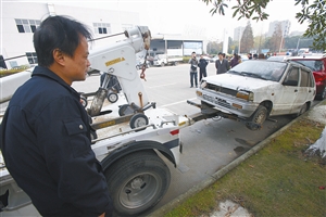 工作人员用拖车将段塘西路停放的一辆“僵尸车”拖走