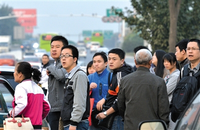 沒擠上的乘客翹首企盼下一輛公交車的到來。