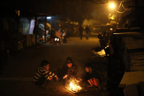 印度首都遭遇低温，小孩子围在一起烧火取暖。
