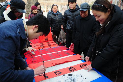 1月13日,在山东省聊城市人民公园,大学生志愿者在现场书写春联进行
