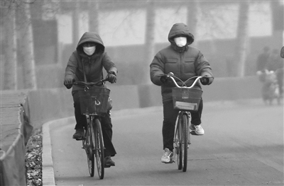 昨日，菜户营桥东行人戴着口罩在雾霾中骑行。