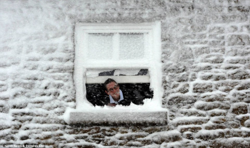 白雪覆盖房屋,该男子探头观看窗外雪景.