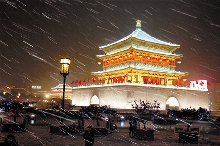 这是2月6日拍摄的雪中西安地标建筑钟楼(右),鼓楼夜景.