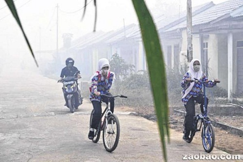 印尼西加里曼丹省首府坤甸近来被烟霾笼罩，居民出入都要遮脸罩口。