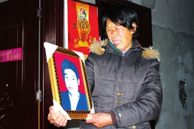 贾有强的母亲抱着儿子的遗像悲痛万分