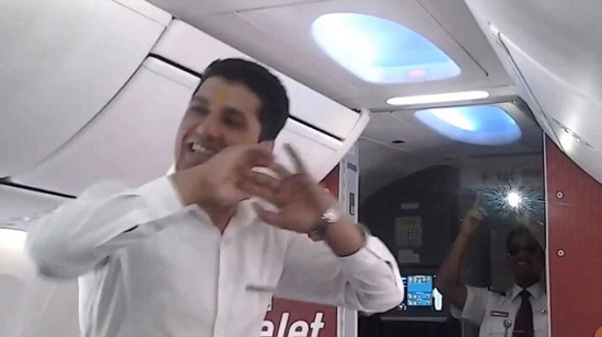 图中可以看到节日当天这家印度航班的机组人员在机舱走道跳舞娱乐乘客，一名飞行员走出驾驶舱，用手机拍摄跳舞场面。