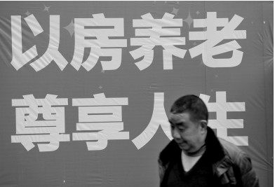 2014年2月25日，重庆某公司推出“以房养老创新模式”，一位市民出现在其宣传语前（资料图片）。 图/CFP