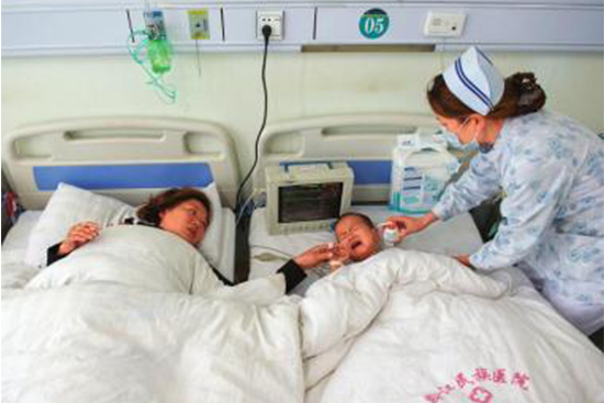 奶奶李从英和小孙子吴金泓（中）在黔江区民族医院接受治疗。