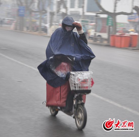 25日下午,市民身穿雨披骑行在路上