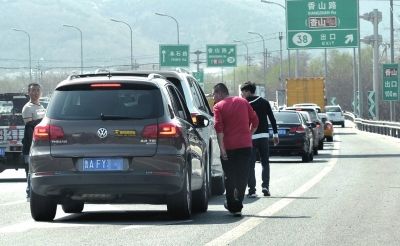 村导正在询问堵在路上的游客。京华时报记者