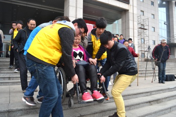 成立大会结束后,志愿者们帮助残疾朋友下楼梯.